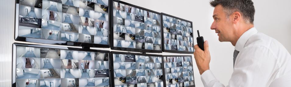 A man talking on a radio while looking at CCTV feeds