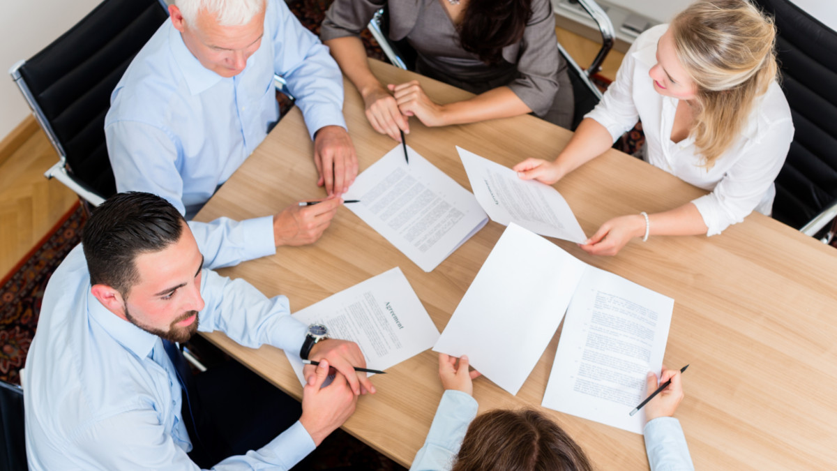 A group of people going over contracts in a board meeting