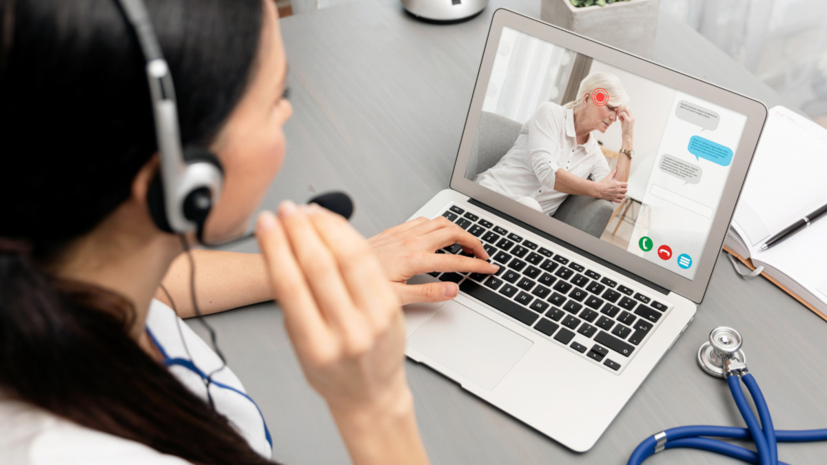 A healthcare provider talking with an elderly patient over a video call on her laptop