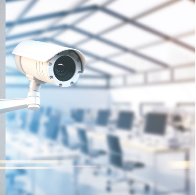 A security camera with a blurred background of desks and chairs